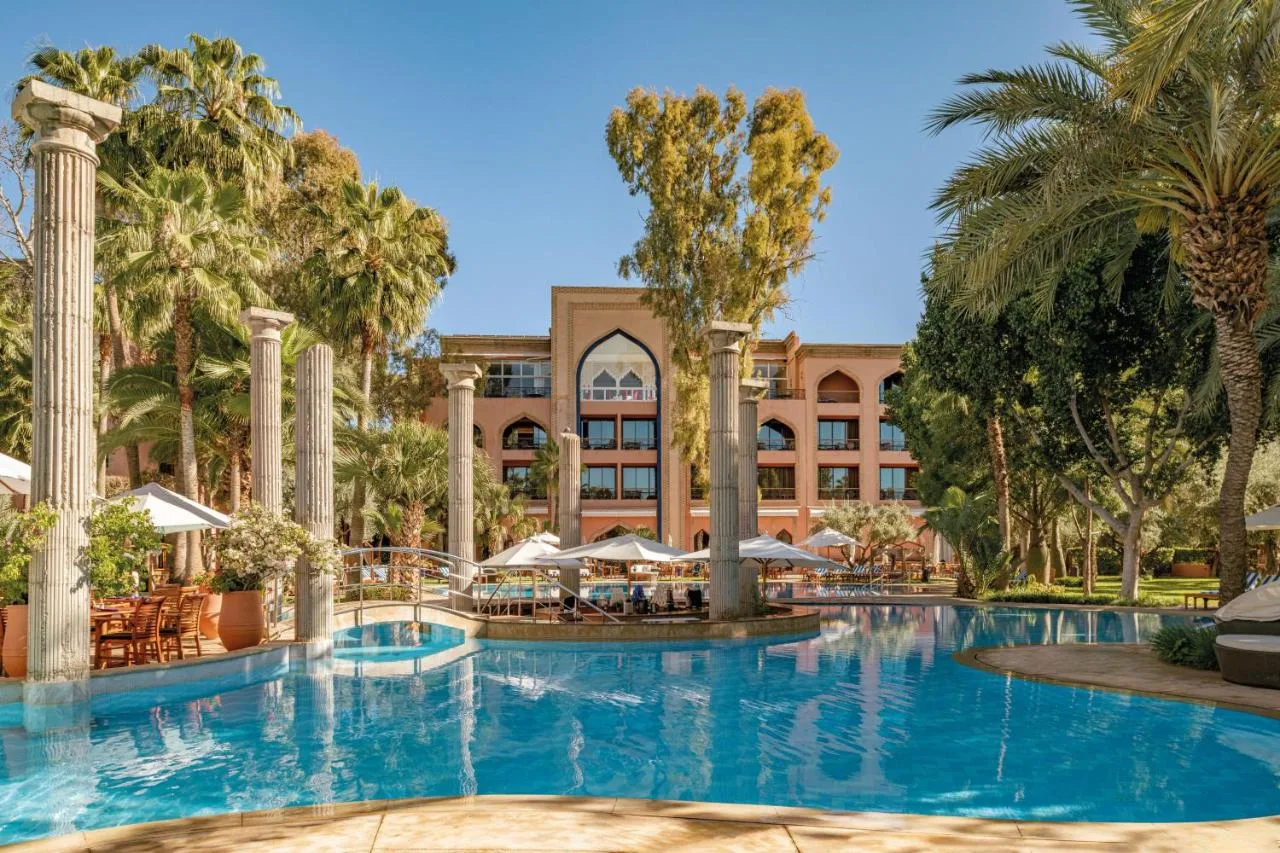 Von Säulen gesäumter Pool des Es Saadi Marrakech Resort vor dem Palast und Palmen