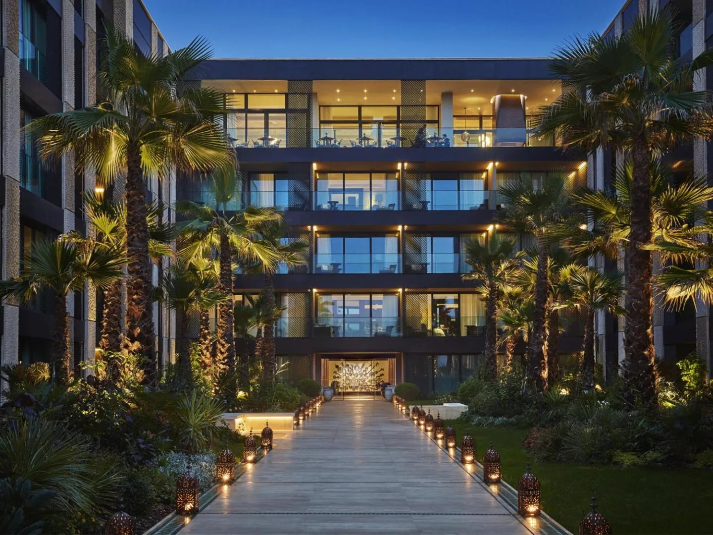 Lit path lined with palm trees leading to the entrance of the Four Seasons Hotel Casablanca