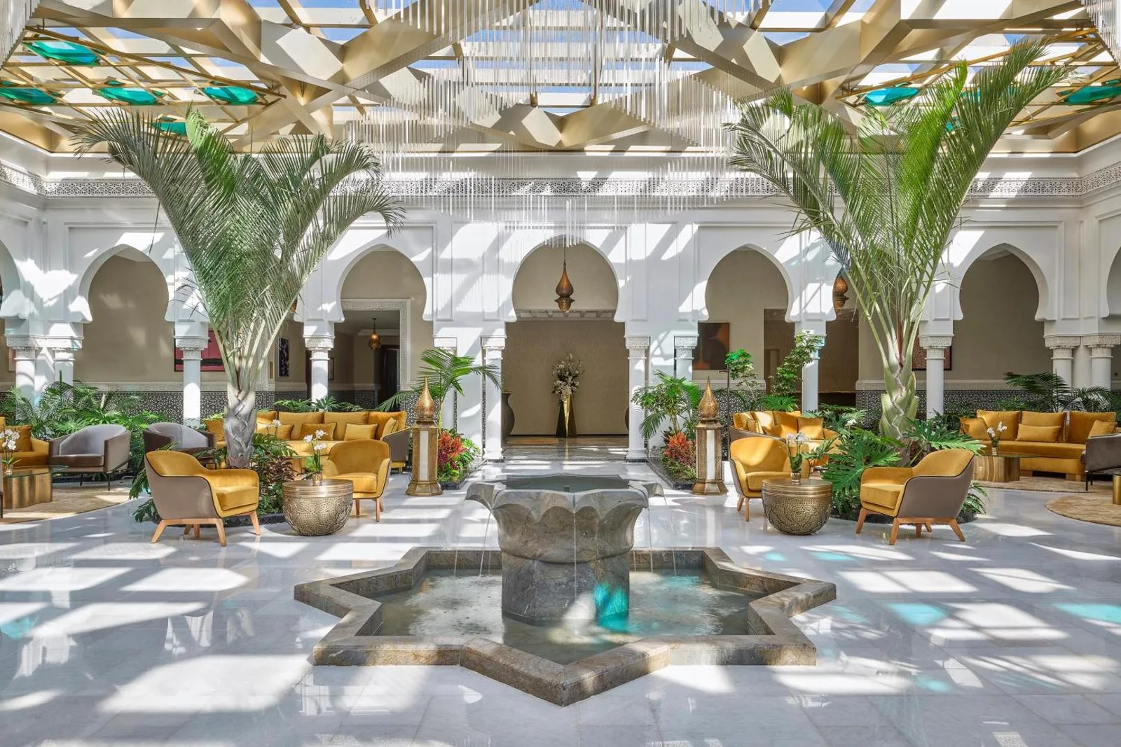 Arcaded atrium of the Four Seasons Hotel Rabat at Kasr Al Bahr with a star-shaped fountain, palm trees and a glazed ceiling