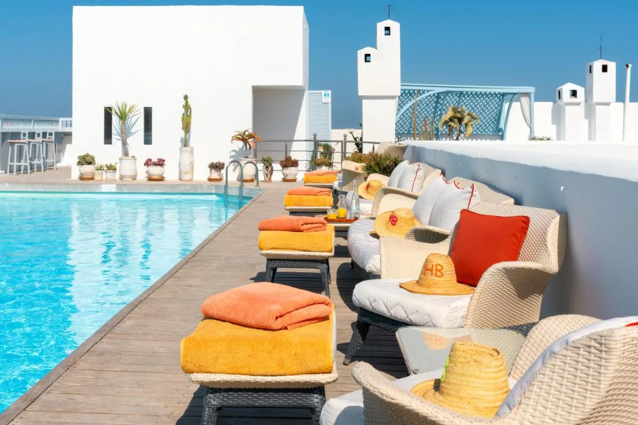 Rooftop pool at Heure Bleue Palais, lined with loungers and orange cushions