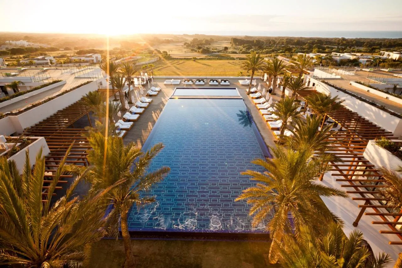 Long pool at Hotel Le Golf d'Essaouira lined with palm trees, at sunset
