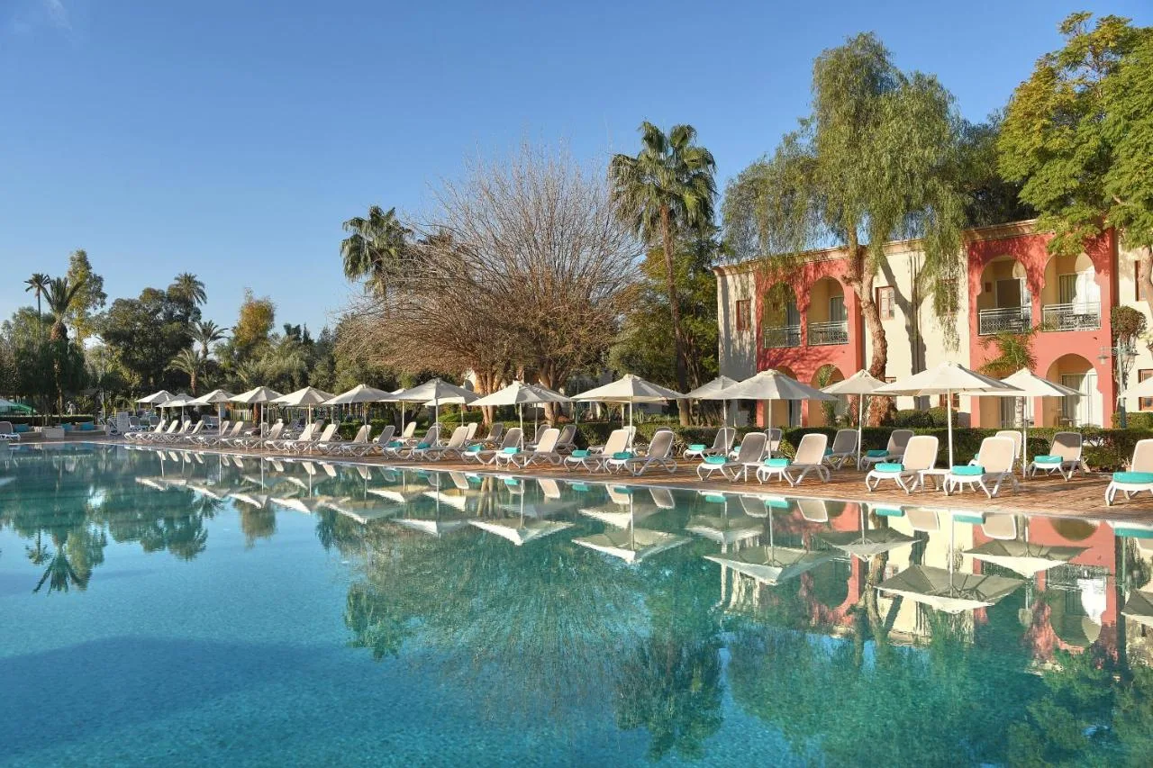 Großer Pool des Iberostar Waves Club Palmeraie Marrakech, in dem sich Palmen und Schirme spiegeln