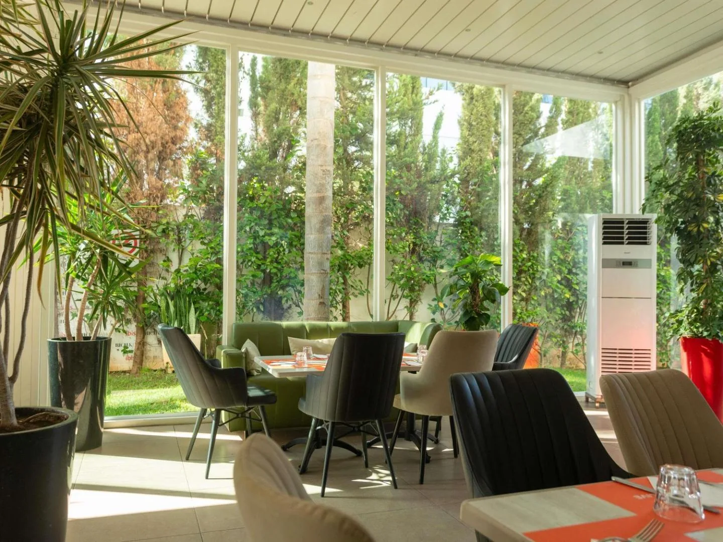 Glass-walled dining room at the ibis Rabat Agdal opening onto the garden, with tables and chairs