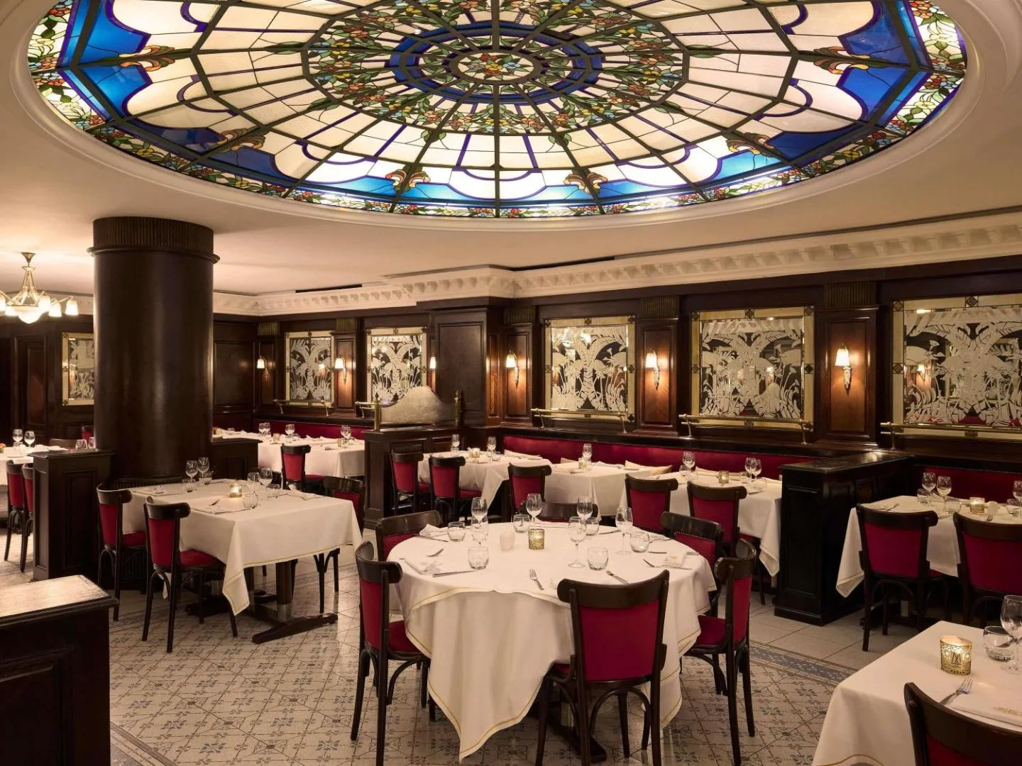 Restaurant room at Le Diwan Rabat hotel under a stained-glass dome, with wood panelling and red banquettes