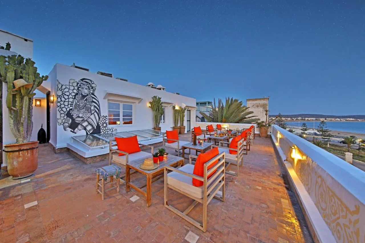 Terrace of Madada Mogador with orange armchairs and a mural, facing the bay