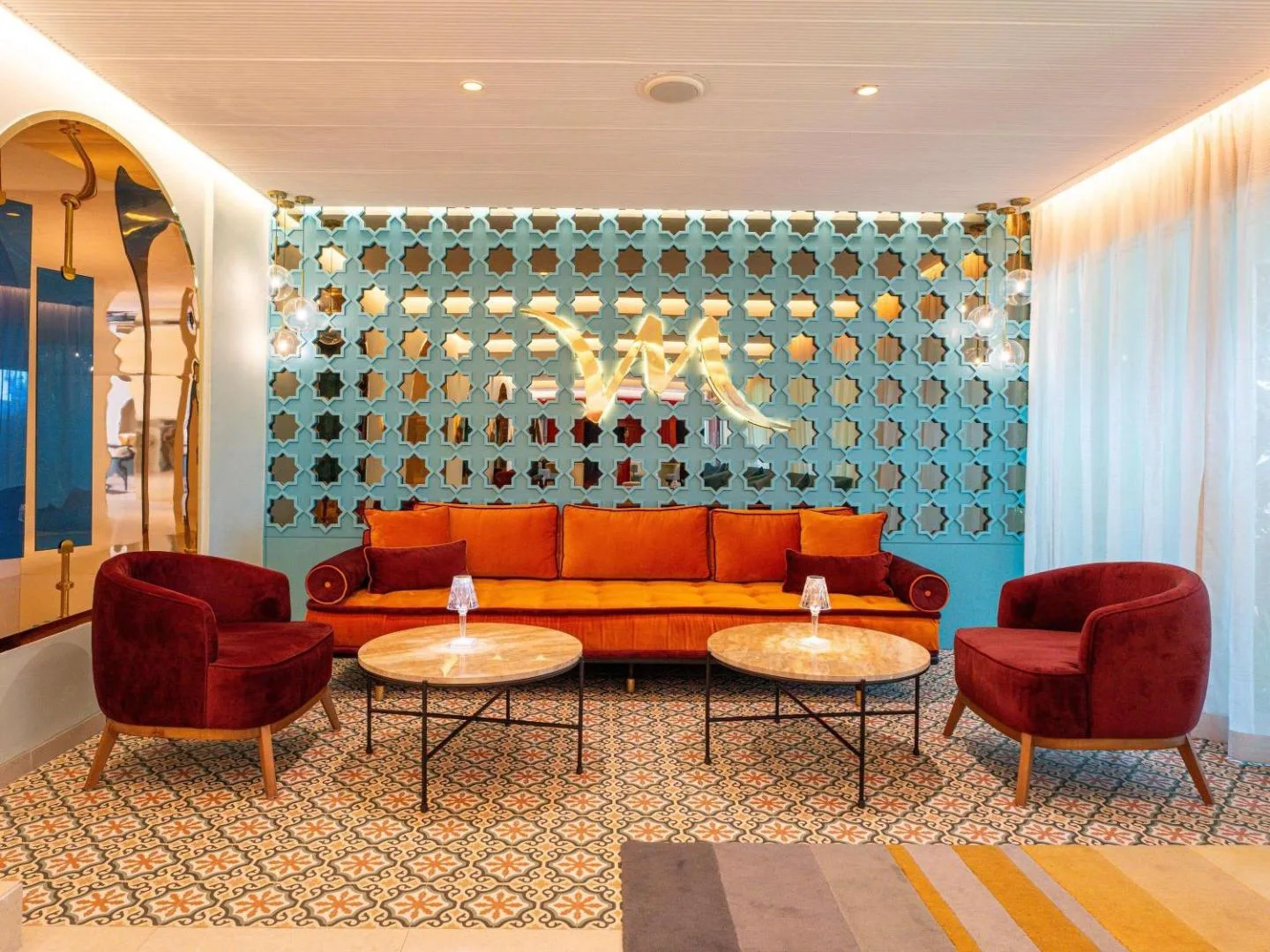 Lounge at the Mercure Rabat Sheherazade with an orange sofa, burgundy armchairs and a turquoise lattice screen