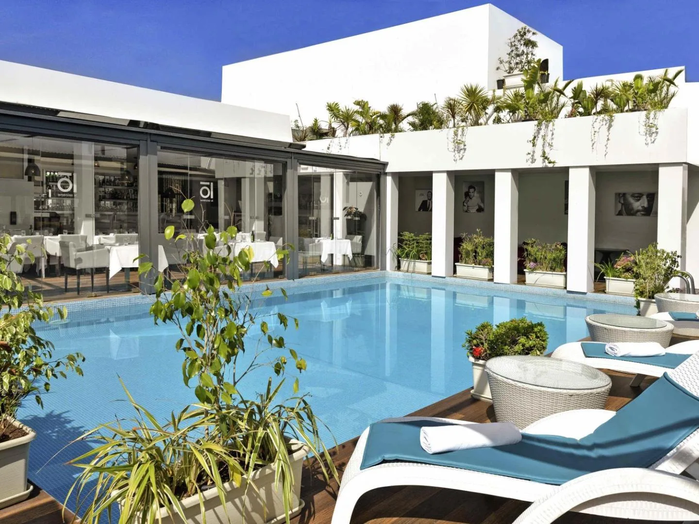 Terrace pool at the Mövenpick Hotel Casablanca, lined with plants, with the restaurant behind
