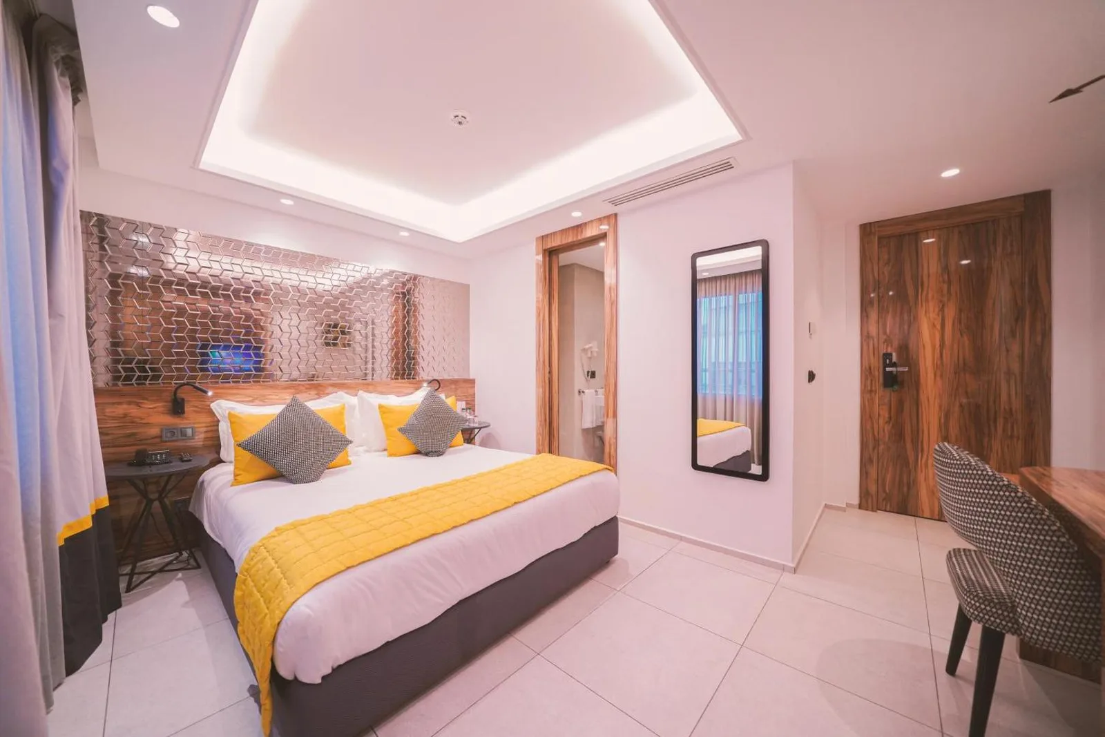 Room at the Oum Palace Hotel & Spa with a mirrored headboard, yellow throw and wood panelling