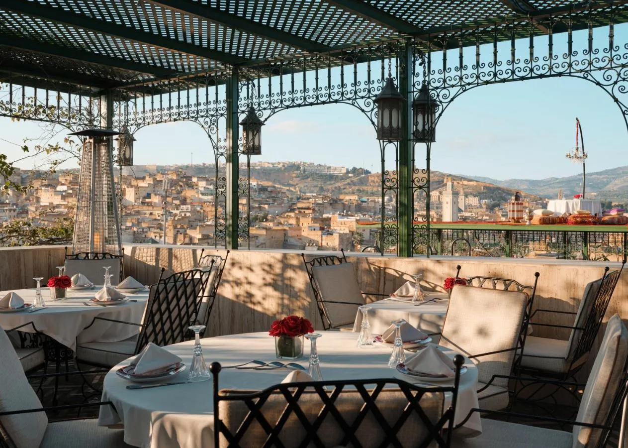 Restaurantterrasse des Palais de Fès mit gedeckten Tischen unter einer Pergola vor der Medina