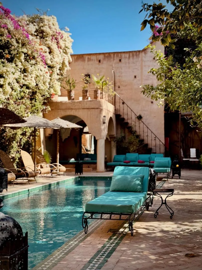 Courtyard of the Palais Oumensour in Taroudant: pool, turquoise cushions and a staircase with ochre walls