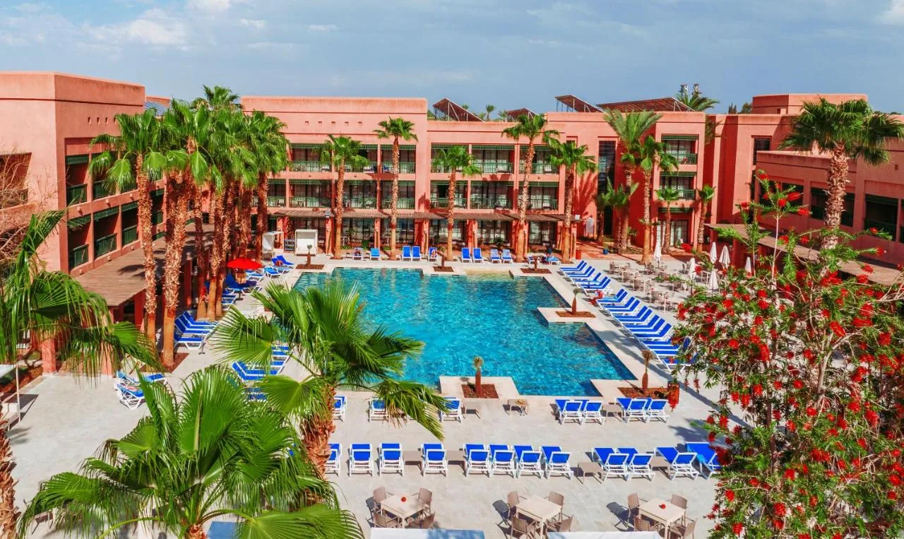 Luftaufnahme des Pools des Pickalbatros Hôtel du Golf zwischen ockerfarbenen Gebäuden und Palmen