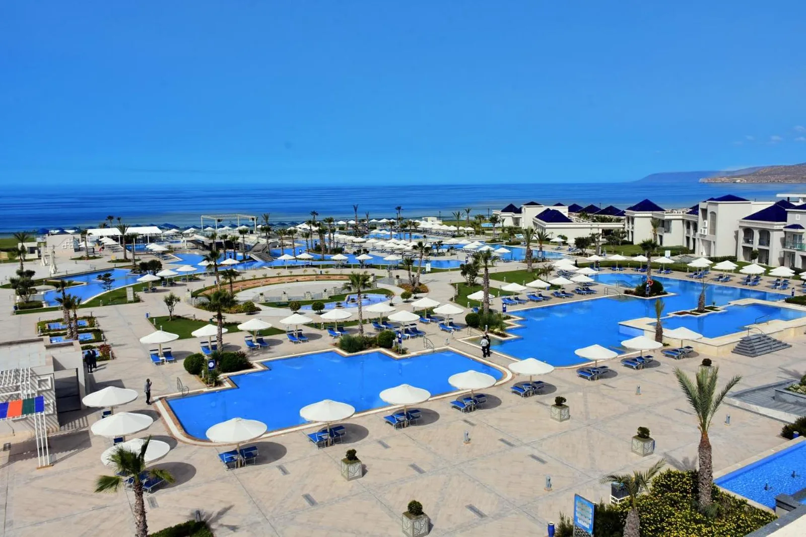 Pools and blue-roofed buildings at the Pickalbatros White Beach Taghazout, facing the ocean