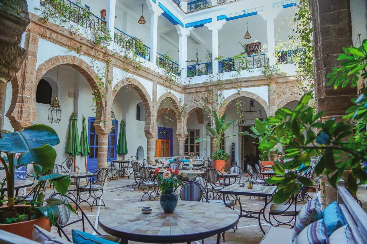 Arcaded patio of Riad Al Madina, with tables, plants and balustraded galleries