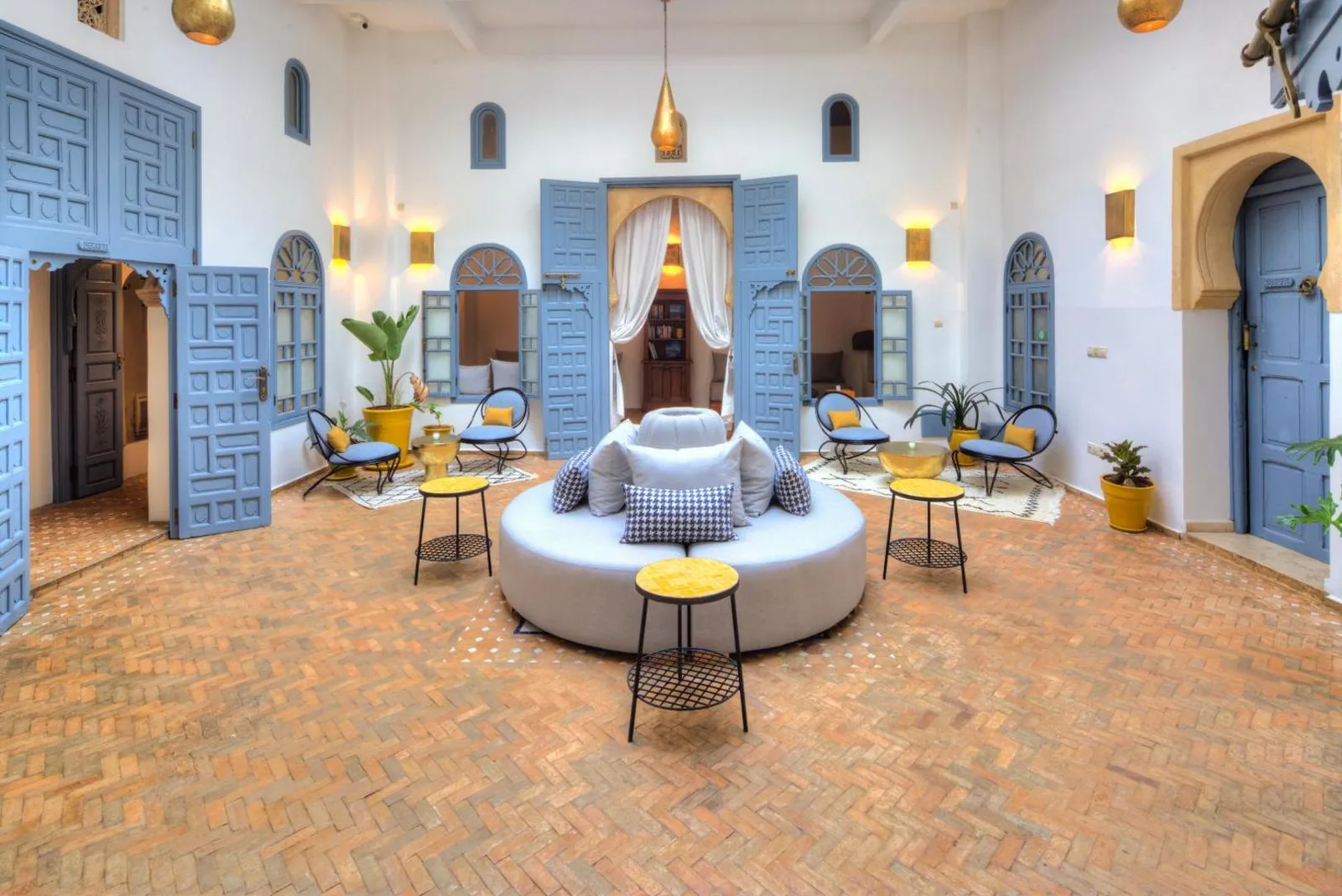 Courtyard of Riad Amaris with its brick floor, round sofa and blue doors