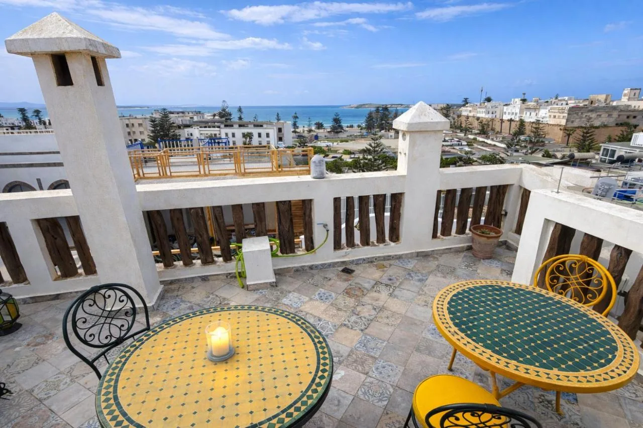 Terrace of Riad Chama with mosaic tables, overlooking the rooftops and the sea