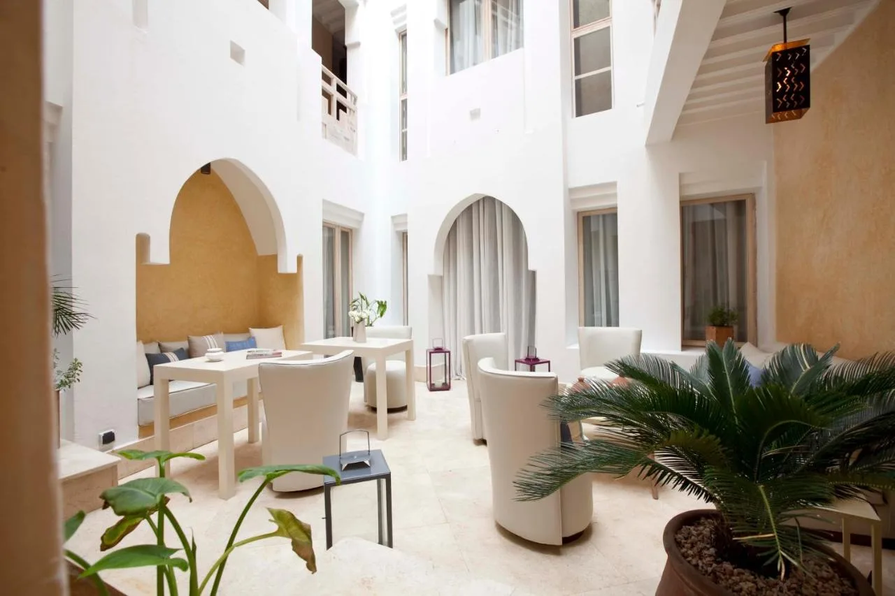 White patio of Riad Dar Maya with seating areas, plants and arcaded galleries