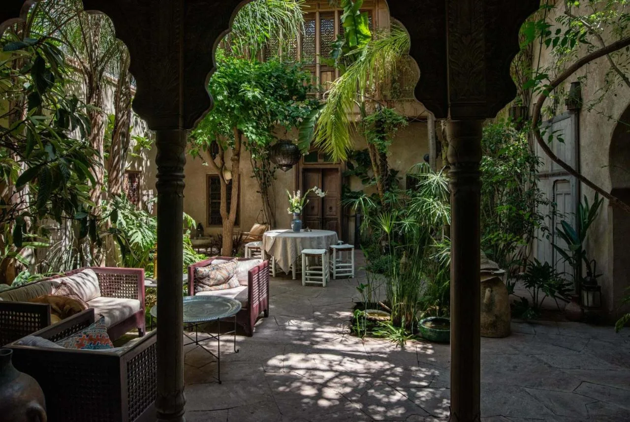 Begrünter Innenhof des Riad Kbour & Chou zwischen Holzbögen, mit Kletterpflanzen und Sitzecke