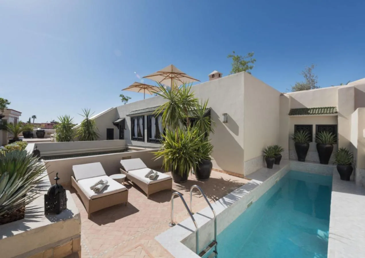 Dachterrasse des Riad Kheirredine mit türkisfarbenem Becken, Sonnenliegen und Topfpflanzen
