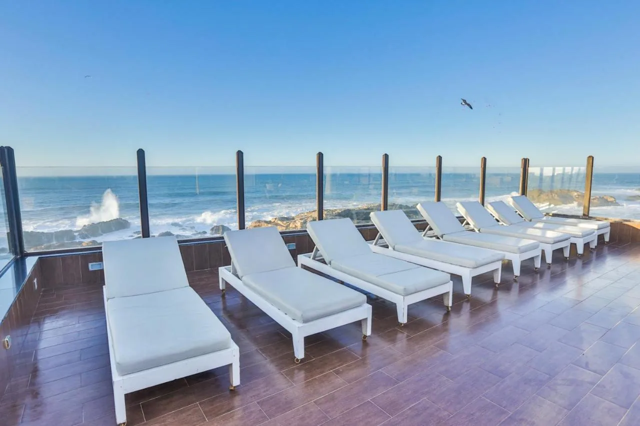 Terrace of Riad Mimouna with white loungers facing the ocean and the waves