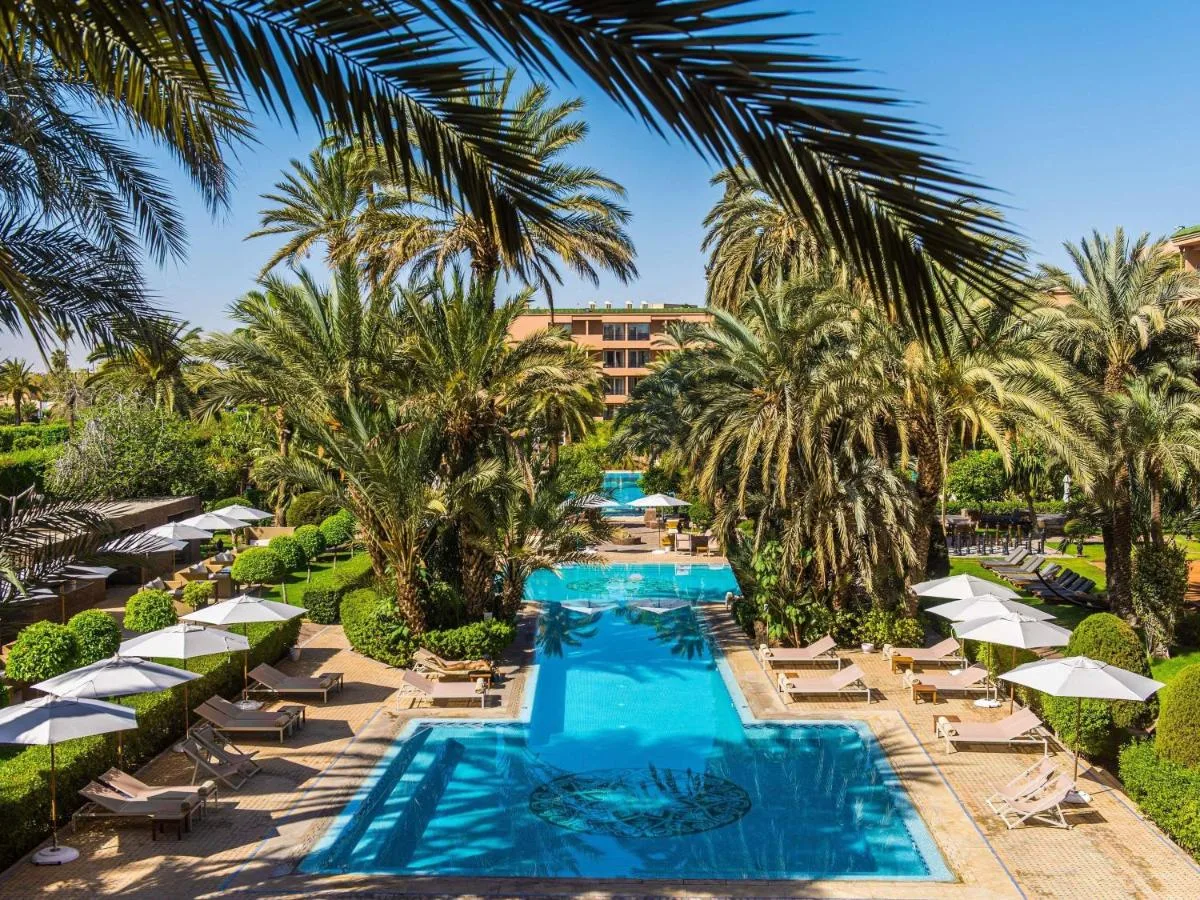 Pool des Sofitel Marrakech Palais Impérial von oben, umgeben von Palmen und Sonnenschirmen