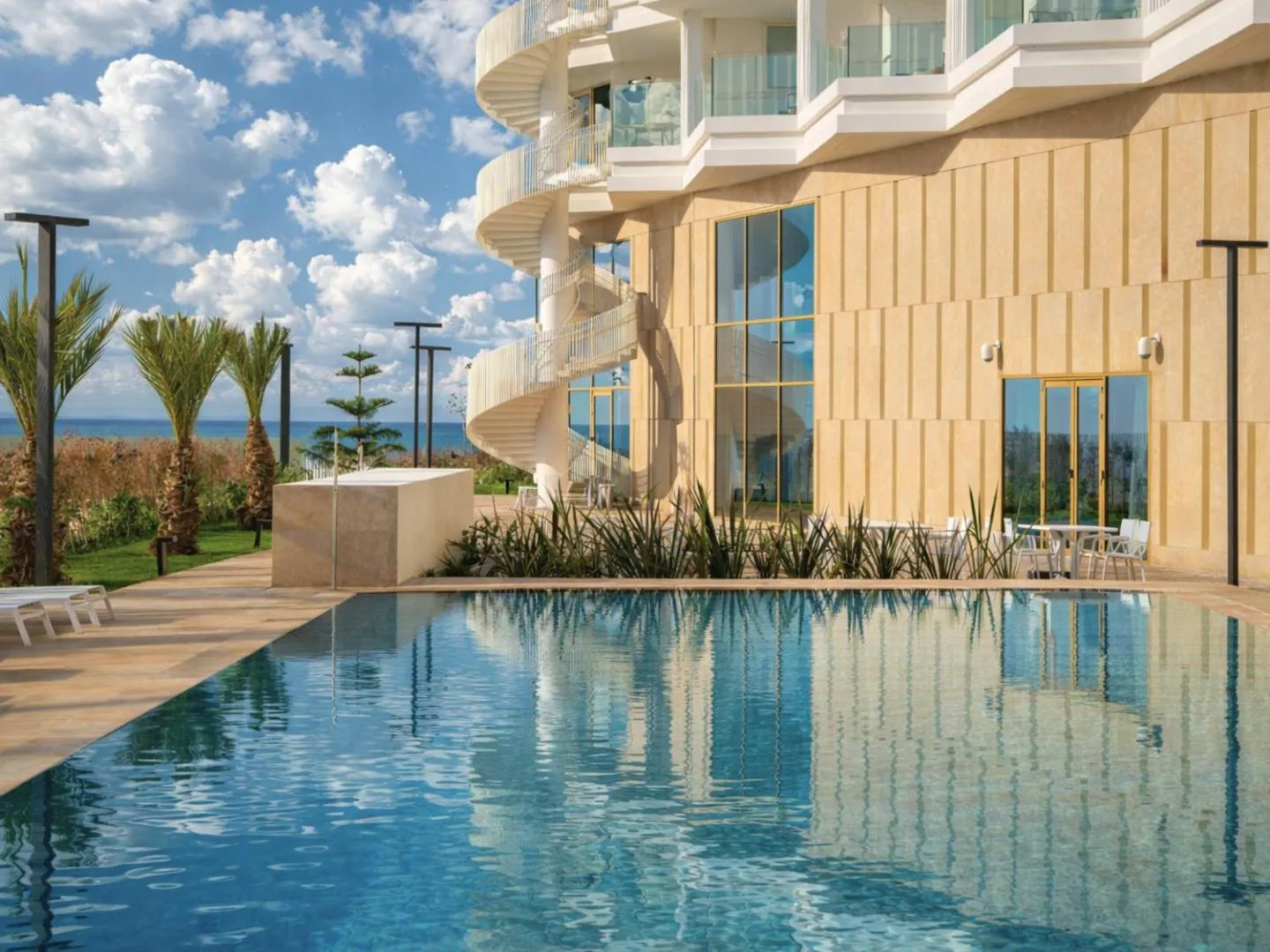 Pool and light stone façade of STORY Le Carrousel Rabat with its spiral staircase, facing the ocean