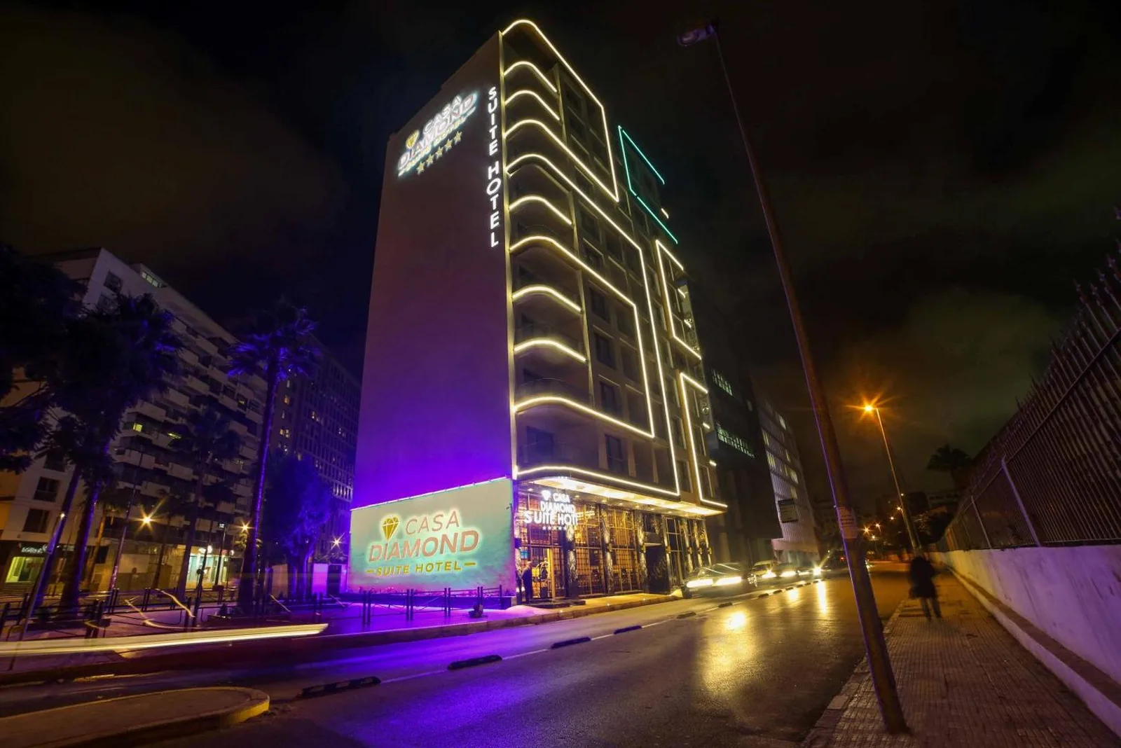 Illuminated façade of the Suite Hôtel Casa Diamond at night with its sign and lines of light