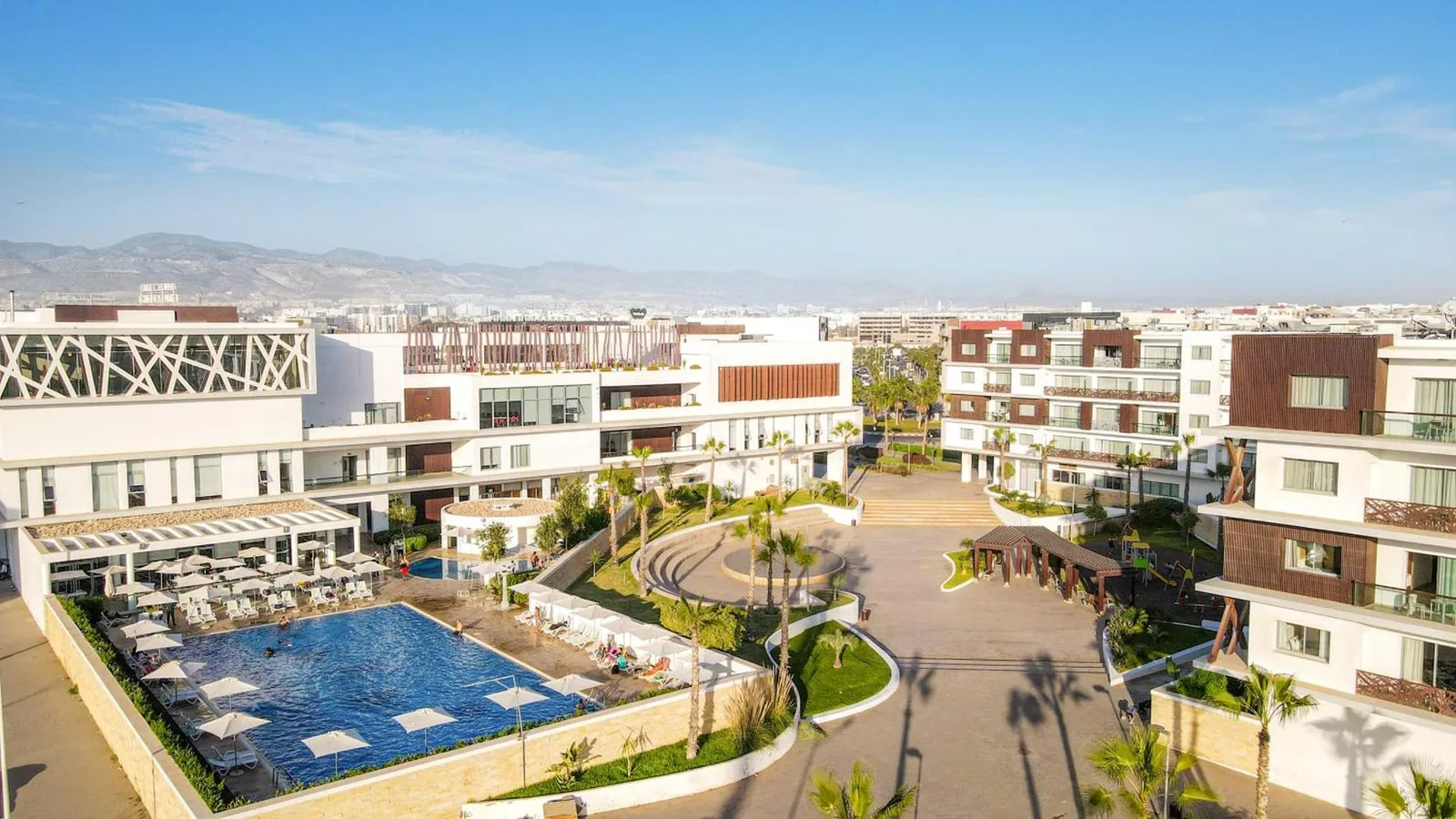 Elevated view of the Zephyr Agadir complex: pool, residences and mountains in the distance