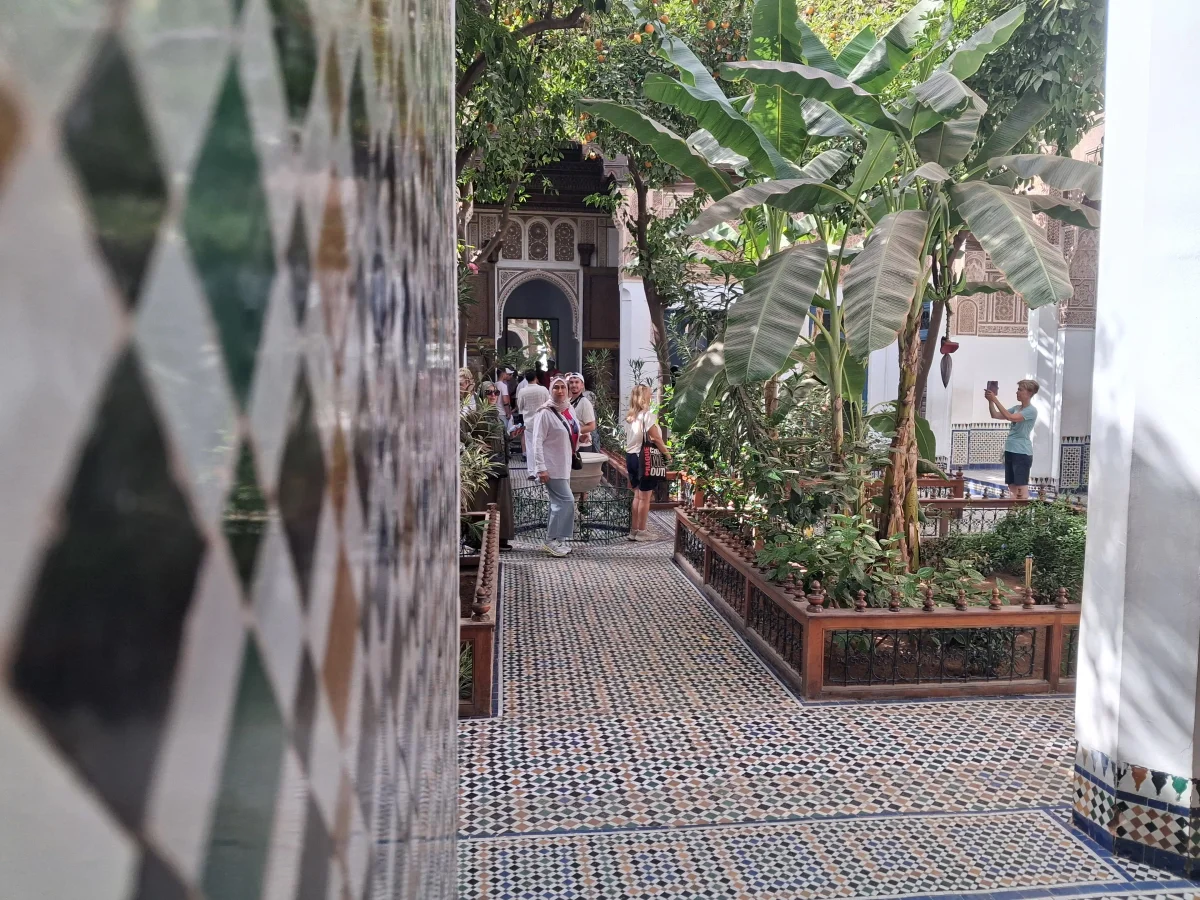 Innengarten des Bahia-Palastes in Marrakesch mit traditionellem Zellige-Mosaik und Besuchern am Morgen.