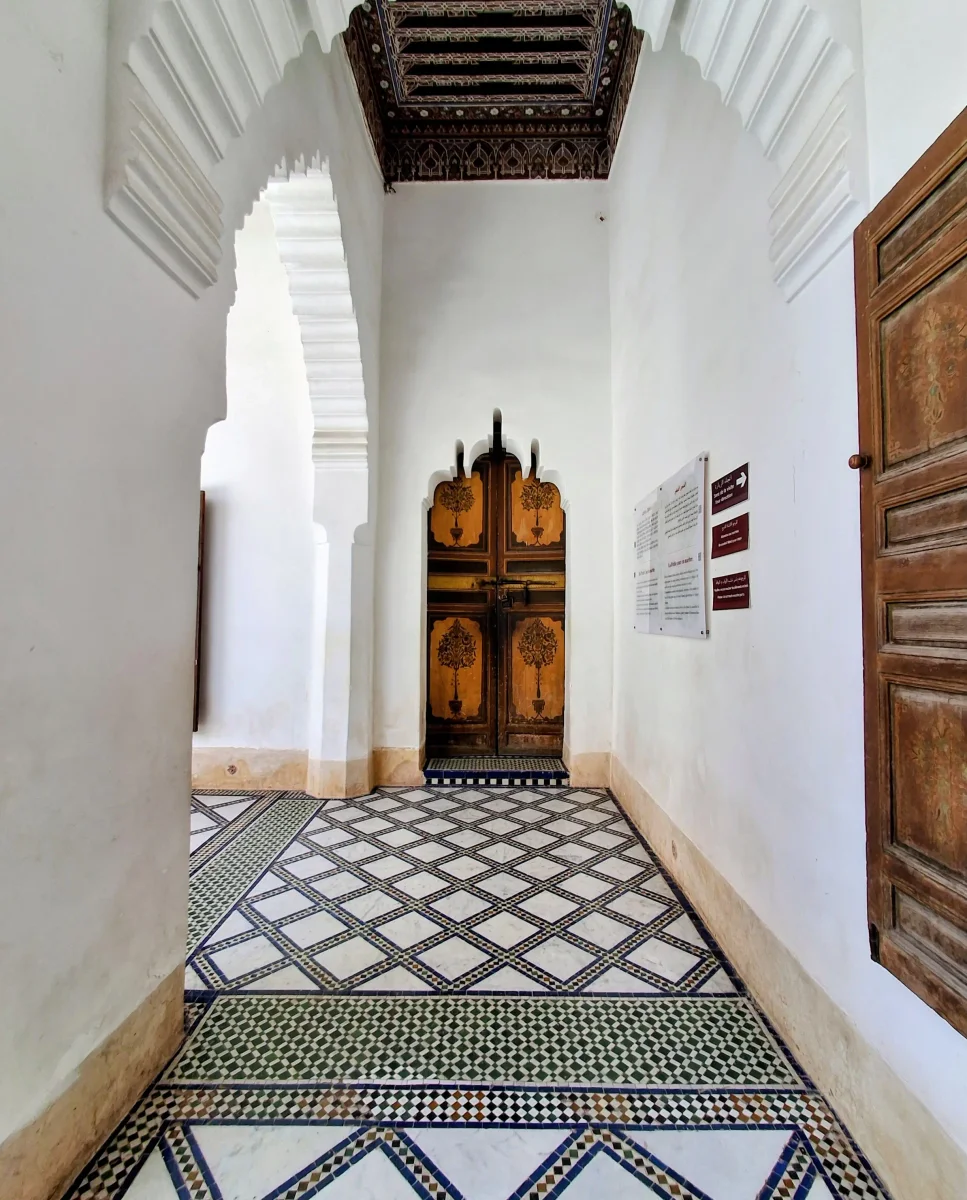Geschnitzte Holztür und traditionelle Stuckverzierung in einem Korridor des Bahia-Palastes in Marrakesch.