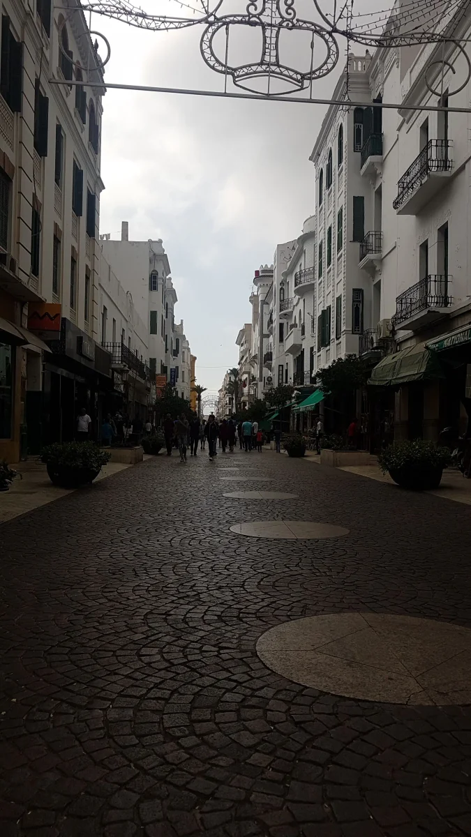 Vue de la rue piétonne pavée emblématique du quartier de la médina de Tétouan, bordée d'immeubles blancs traditionnels.