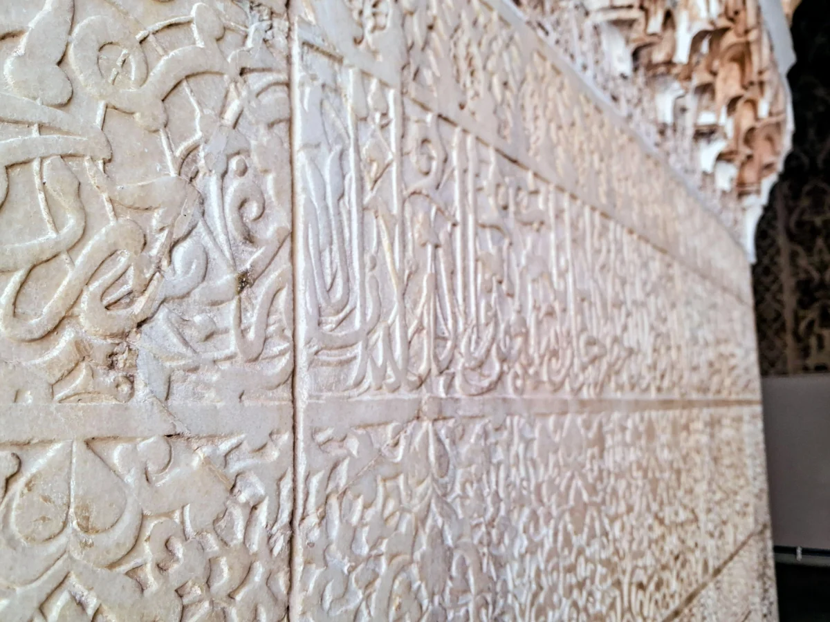 Close-up of finely carved stucco walls featuring traditional Moroccan geometric and calligraphic patterns.