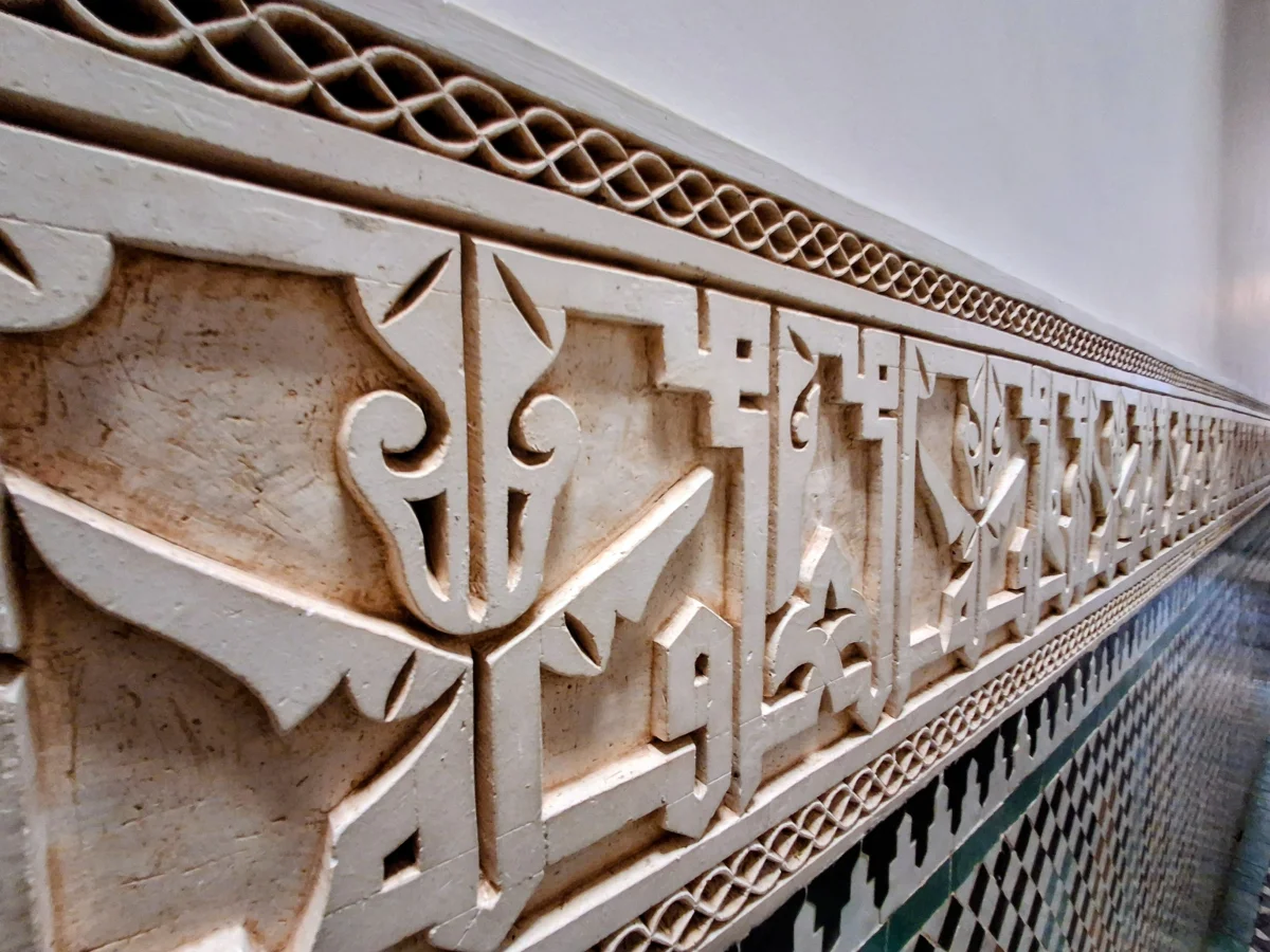 Close-up of a carved stucco frieze featuring Arabic calligraphy and traditional geometric ornament.