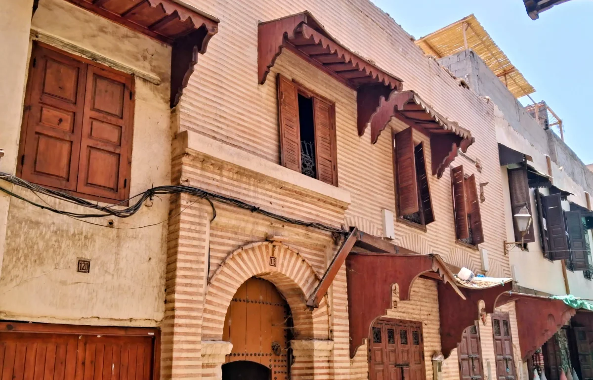 Fassaden traditioneller Gebäude mit überdachten Holzbalkonen und Holzfenstern in den Straßen des Mellah von Marrakesch.