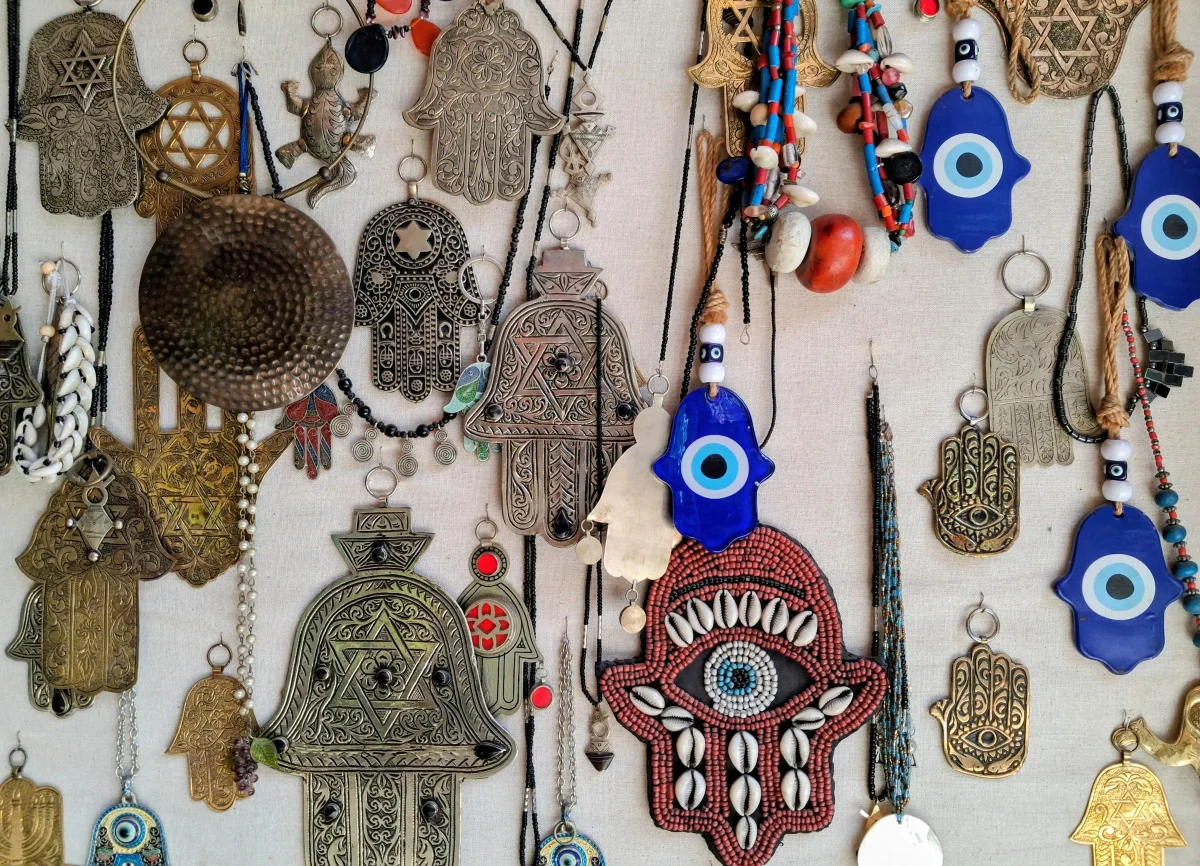 Präsentation traditioneller Handwerksgegenstände im Mellah-Viertel von Marrakesch mit Anhängern, Amuletten, Khamsa-Symbolen und Schutztalismanen.