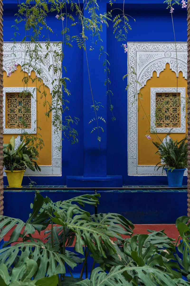 architecturaux marocains vibrants bleus et jaunes entourés d'une végétation luxuriante.