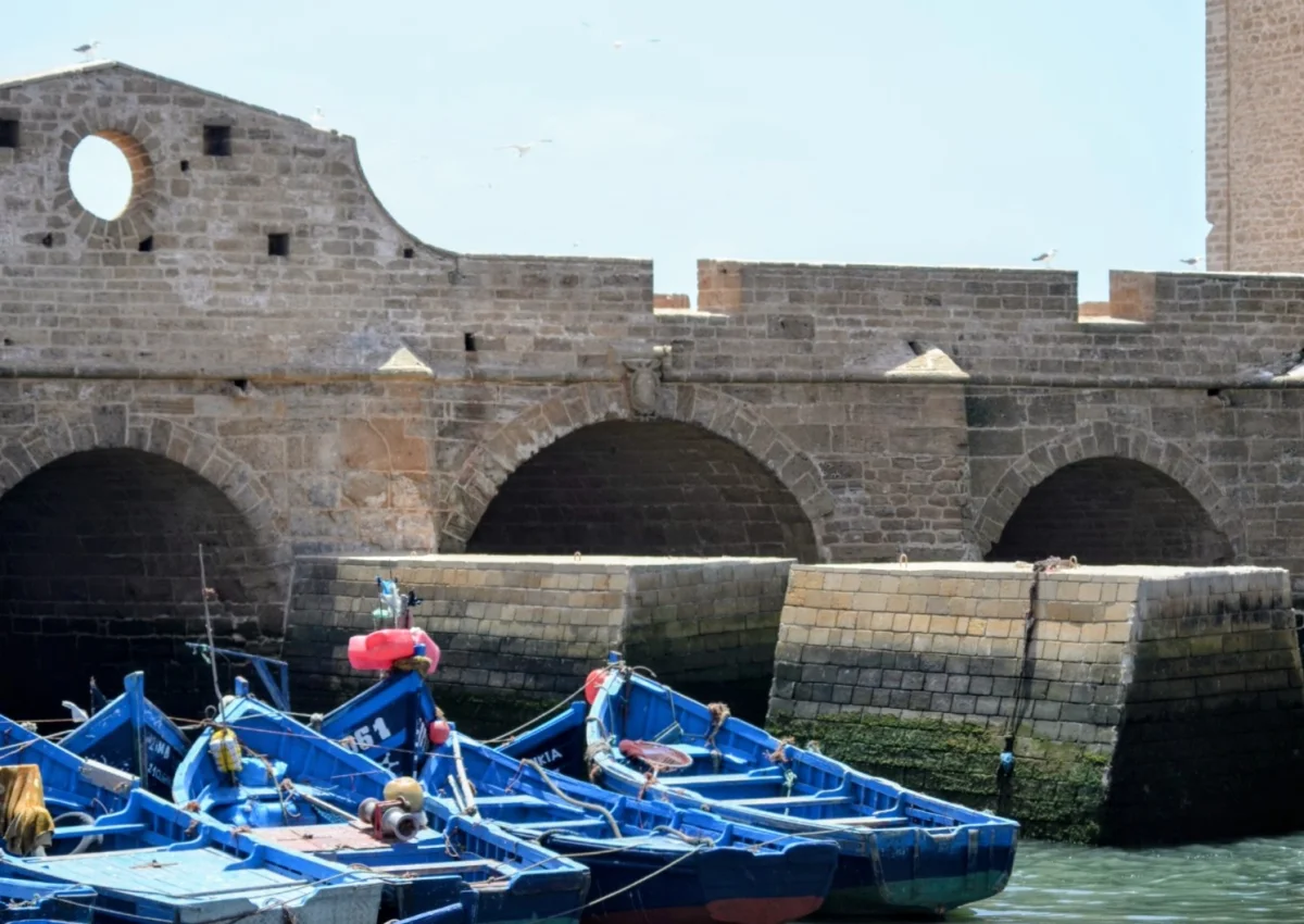 Vue sur les arches fortifiées en pierre de taille du port d'Essaouira sous un ciel ensoleillé.