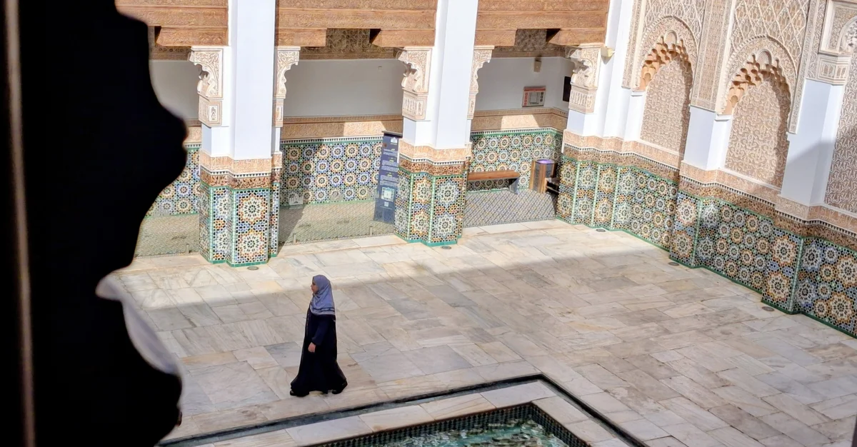 Innenhof der Medersa Ben Youssef in Marrakesch mit Zellige, geschnitztem Stuck und traditioneller marokkanischer Architektur.