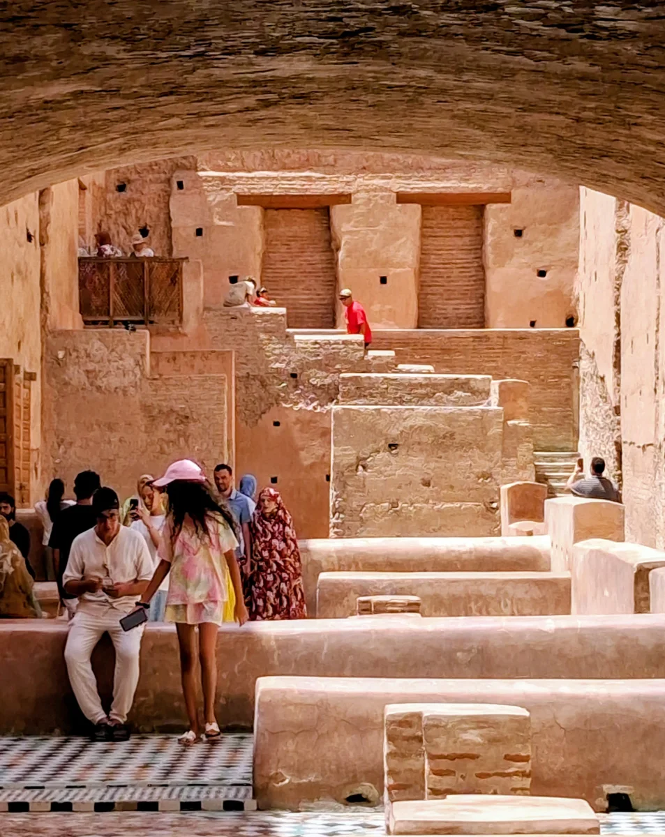 Visiteurs explorant les ruines monumentales et les vastes bassins du Palais El Badi à Marrakech, témoignant de la grandeur de l'architecture saadienne.