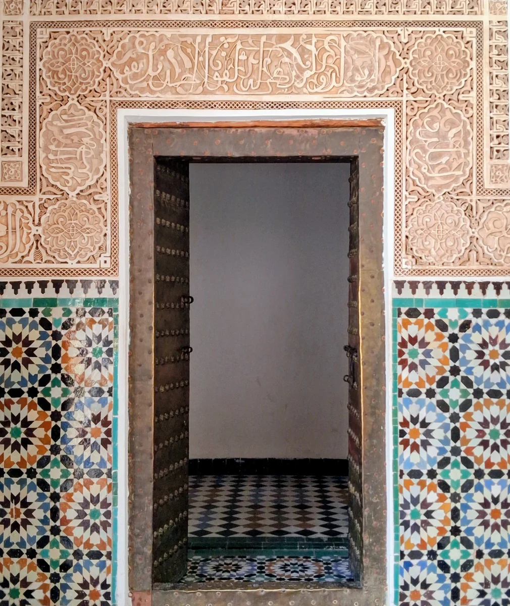 Architektonische Details einer traditionellen marokkanischen Tür mit farbigem geometrischem Zellige und kunstvoll gearbeitetem Stuck.